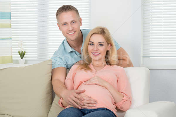 Happy Expecting Couple Sitting On Sofa At Home Stock photo © AndreyPopov