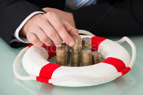 Person Holding Stack Of Coins With Lifebelt Stock photo © AndreyPopov