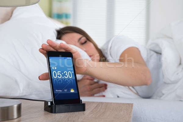 Stock photo: Woman Snoozing Alarm On Mobile Phone Screen