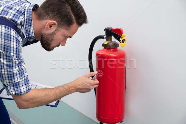 Man Checking Symbol On Fire Extinguisher Stock photo © AndreyPopov