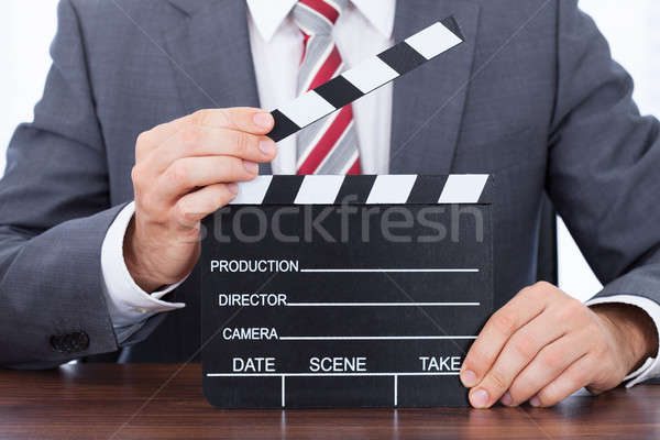 Businessman Holding Clapper Board At Desk Stock photo © AndreyPopov