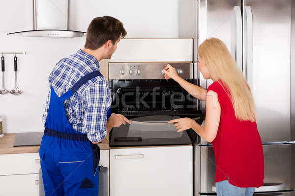 Woman Showing Damage In Oven To Repairman Stock photo © AndreyPopov