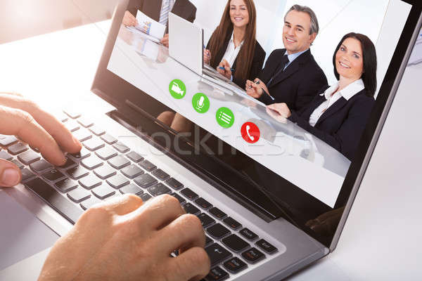 Businessperson's Hand Video Conferencing With Colleagues Stock photo © AndreyPopov