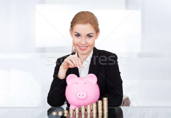 Businesswoman Inserting Coin In Piggybank Stock photo © AndreyPopov