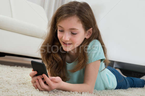 Fille téléphone portable salon fille heureuse tapis enfant [[stock_photo]] © AndreyPopov