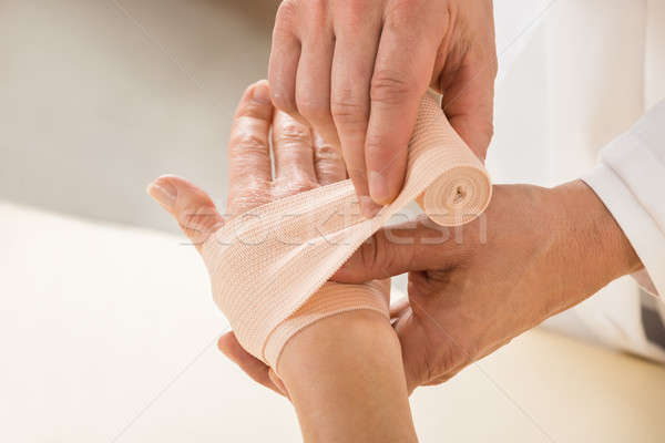 Stock photo: Doctor Wrapping Elastic Bandage To Patient