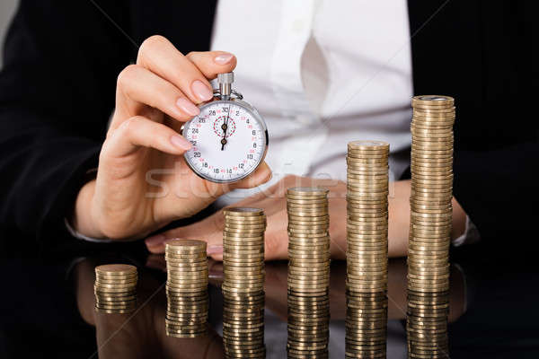 Businesswoman Holding Stopwatch In Front Of Stacked Coin Stock photo © AndreyPopov