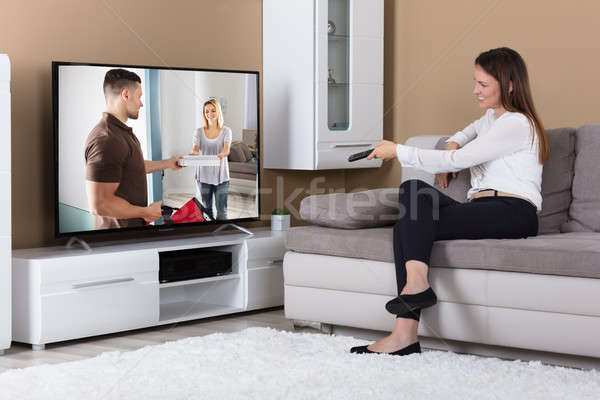 微笑的女人 坐在 沙發 看電視 快樂 年輕 商業照片 © AndreyPopov