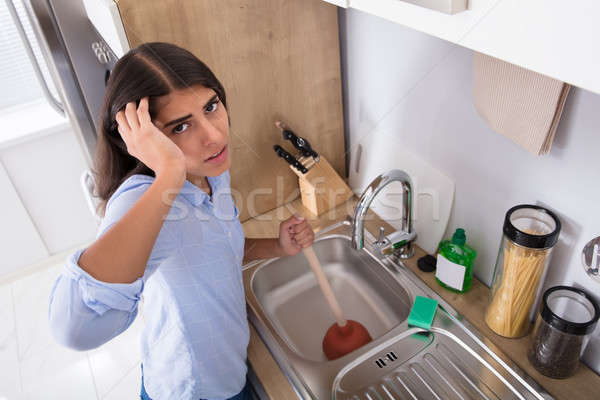 Unhappy Woman Using Plunger In Clogged Sink Stock photo © AndreyPopov