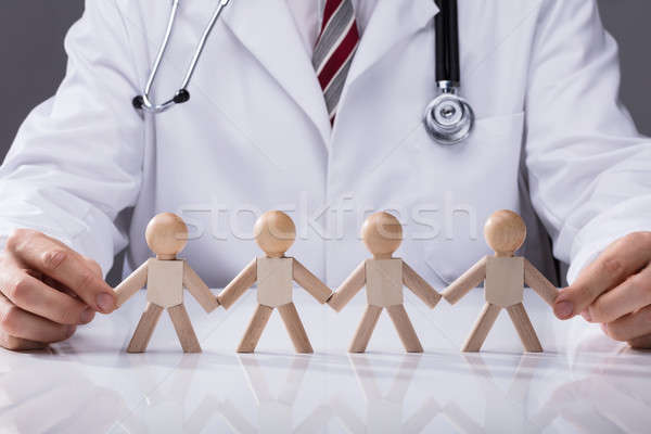 Doctor's Hand Holding Hand Of Wooden Figures Stock photo © AndreyPopov