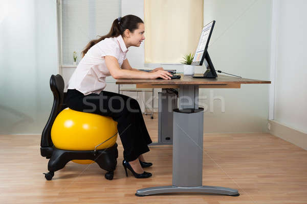 Stock photo: Businesswoman Bending While Sitting On Fitness Ball