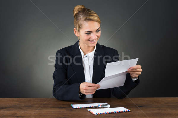 Foto stock: Jóvenes · mujer · de · negocios · lectura · carta · escritorio · sonriendo