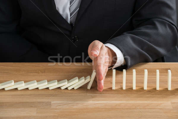 Businessman Stopping Dominoes From Falling Stock photo © AndreyPopov