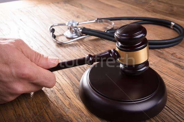 Judge Hand Striking Gavel With Stethoscope At Wooden Desk Stock photo © AndreyPopov