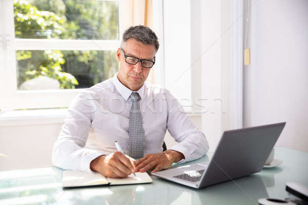 Businessman Writing Schedule In Diary With Pen Stock photo © AndreyPopov