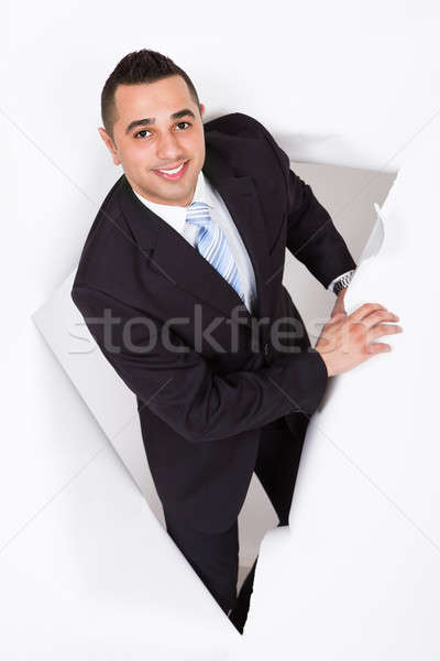 Businessman Emerging Through White Wall Stock photo © AndreyPopov