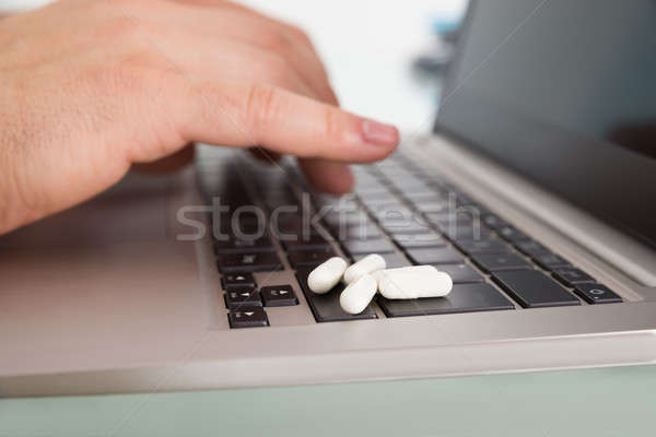 Person Using Laptop With Pills Over Keypad Stock photo © AndreyPopov