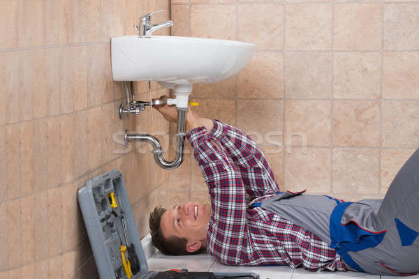 Plumber Lying On Floor Fixing Sink Stock photo © AndreyPopov