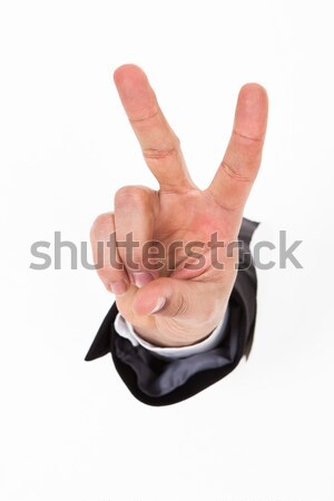 Hand Gesturing Victory Sign Through White Wall Stock photo © AndreyPopov