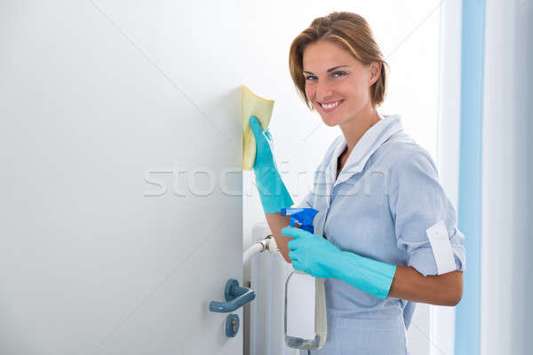 Młodych pokojówka czyszczenia drzwi szczęśliwy butelki Zdjęcia stock © AndreyPopov