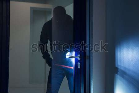 Stock photo: Thief With Flashlight Trying To Break Door