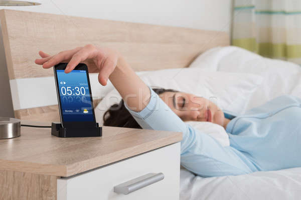 Femeie alarmă telefon mobil pat telefon ceas Imagine de stoc © AndreyPopov