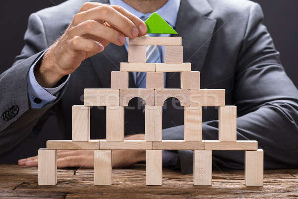 Businessman Making Building With Wooden Blocks Stock photo © AndreyPopov
