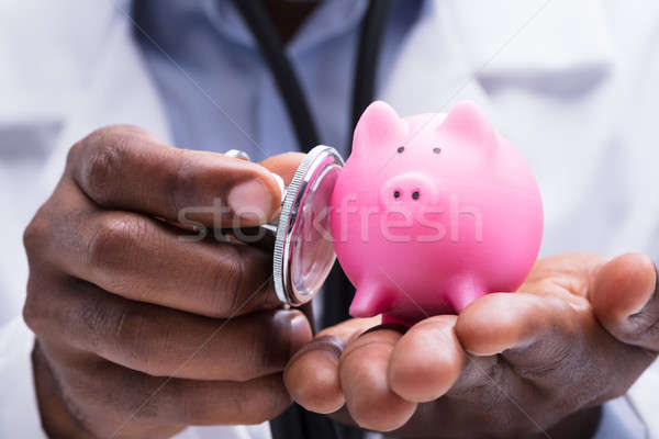 Doctor Examining Miniature Piggybank With Stethoscope Stock photo © AndreyPopov