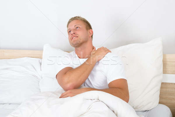 Junger Mann Leiden Schulterschmerzen Porträt Sitzung Bett Stock foto © AndreyPopov