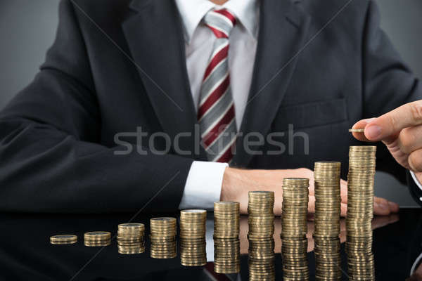 Businessman Placing Coin Over Stack Of Coins Stock photo © AndreyPopov