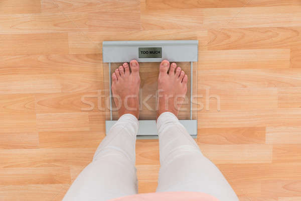 Stock photo: Woman Standing On Weighing Scale