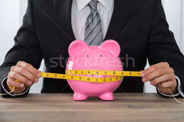 Businessman Measuring Piggybank On Desk Stock photo © AndreyPopov