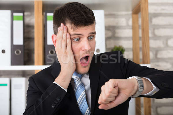 Worried Young Businessman Checking Time In His Watch Stock photo © AndreyPopov