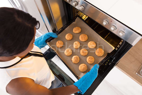 Woman Taking Out Tray Of Baked Cookies From Oven Stock photo © AndreyPopov