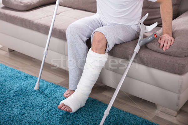 Om picior rupt in sus canapea tânăr carje Imagine de stoc © AndreyPopov