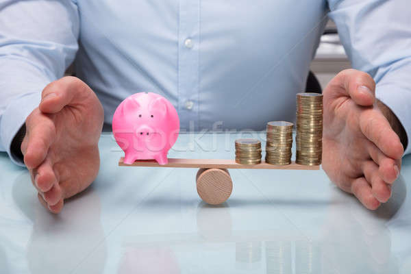 Protecting Balance Between Piggybank And Stacked Coins Stock photo © AndreyPopov