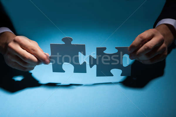 Businessman Joining Puzzle Pieces At Desk Stock photo © AndreyPopov