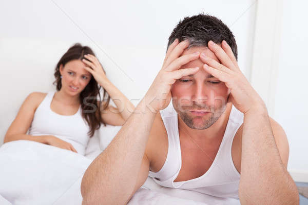 Frustré couple lit homme séance jeune femme [[stock_photo]] © AndreyPopov