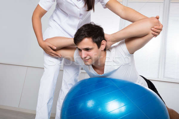 Physiotherapist Assisting Man While Doing Exercise Stock photo © AndreyPopov