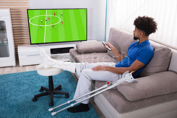 Foto stock: Homem · perna · quebrada · assistindo · futebol · combinar · televisão