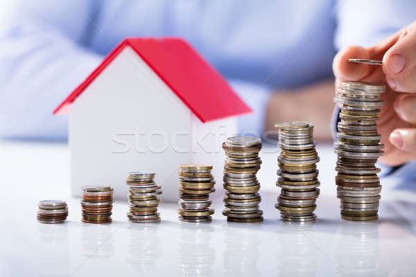 Stock photo: Increased Stack Of Coins In Front Of House Model