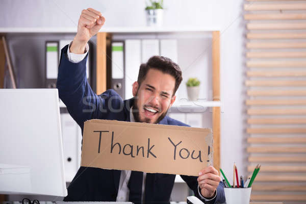 Smiling Young Businessman Holding Cardboard With Thank You Text Stock photo © AndreyPopov