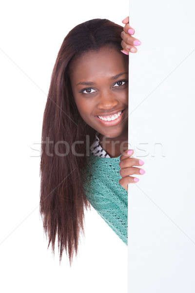 Woman peeping from behind of billboard over white background Stock photo © AndreyPopov