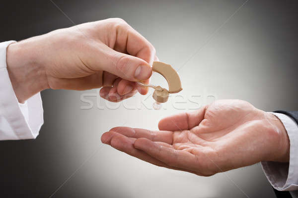 Doctor Giving Hearing Aid To Patient Stock photo © AndreyPopov