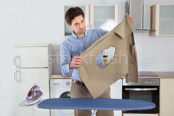 Man Looking At Burned Cloth With Electric Iron Stock photo © AndreyPopov