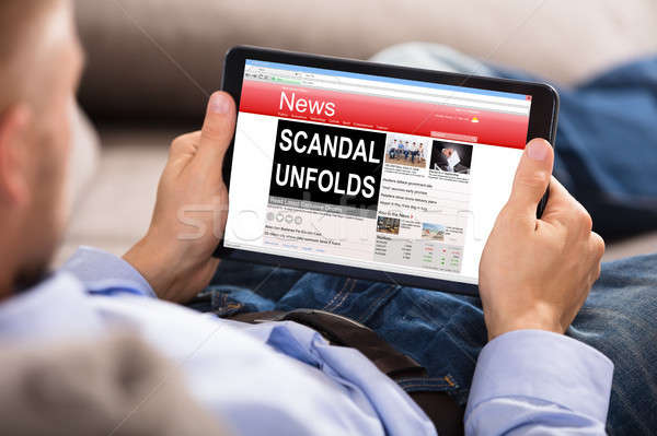 Człowiek czytania skandal wiadomości cyfrowe tabletka Zdjęcia stock © AndreyPopov