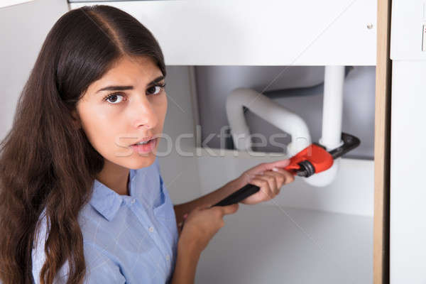 Young Woman Tightening Sink Pipe With Monkey Wrench Stock photo © AndreyPopov