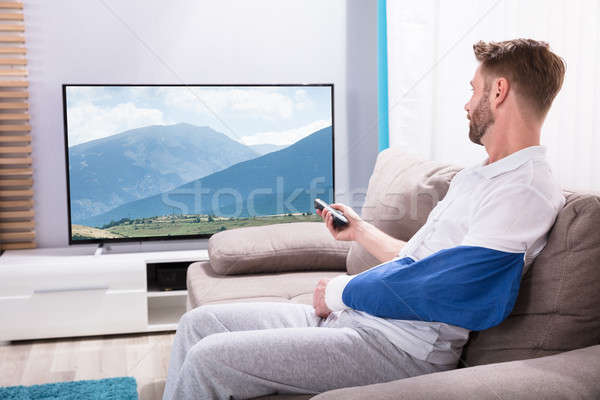 Young Man With Fractured Hand Watching Television At Home Stock photo © AndreyPopov