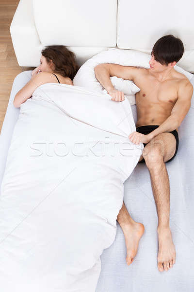 Man Pulling Duvet From Sleeping Woman In Bed Stock photo © AndreyPopov