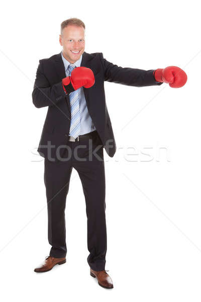 Businessman In Boxing Gloves Punching Over White Background Stock photo © AndreyPopov